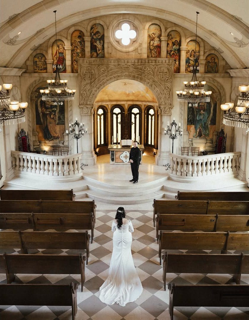 Bride in white dress facing groom at the altar of an ornate church