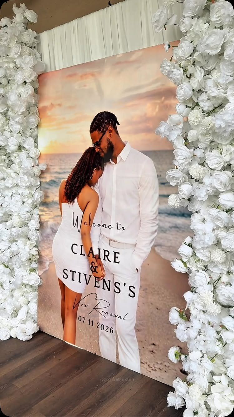 Custom vow renewal backdrop with a couple on a beach framed by white flowers