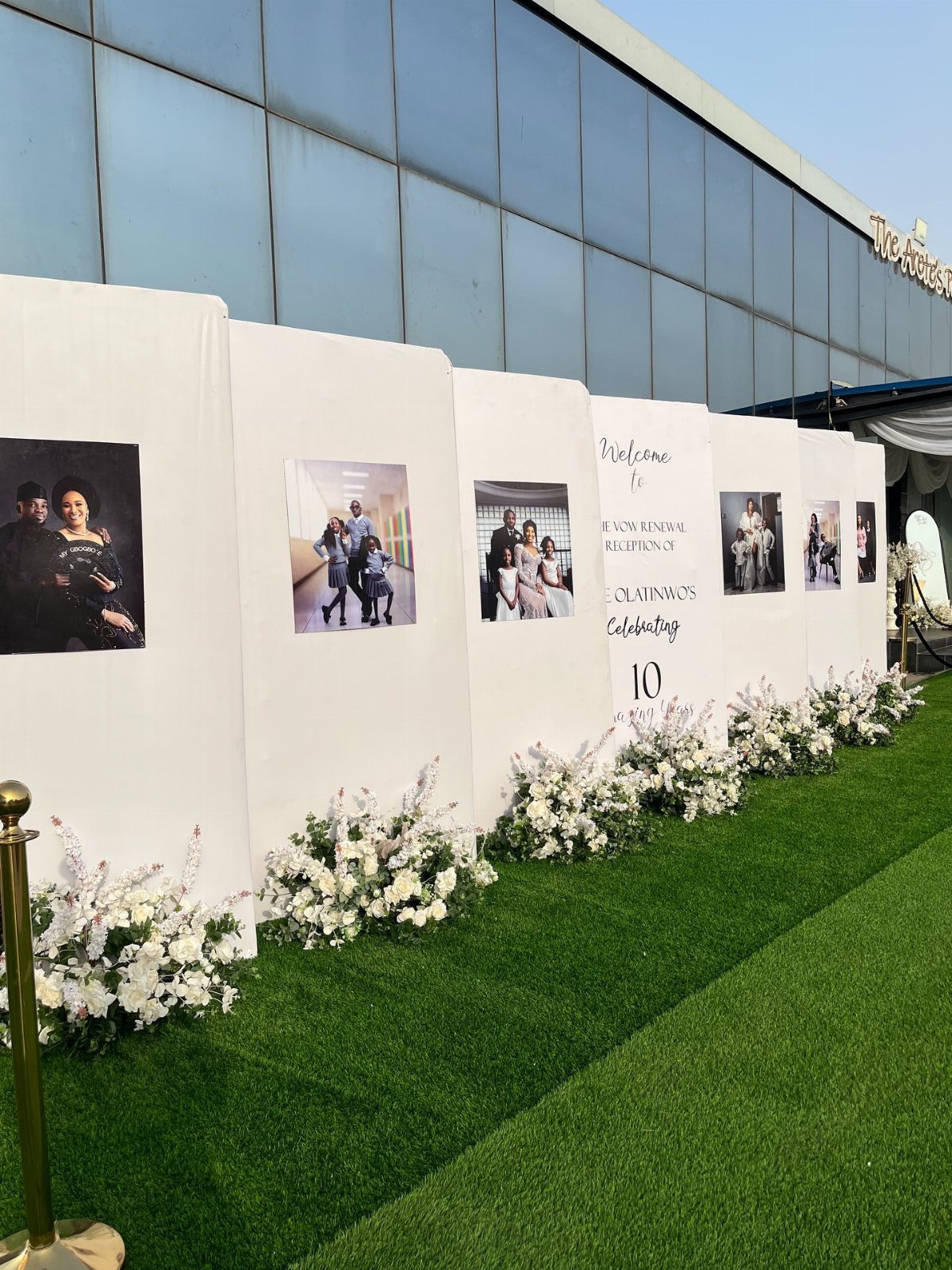 White display panels with family photos and white flowers on green grass.