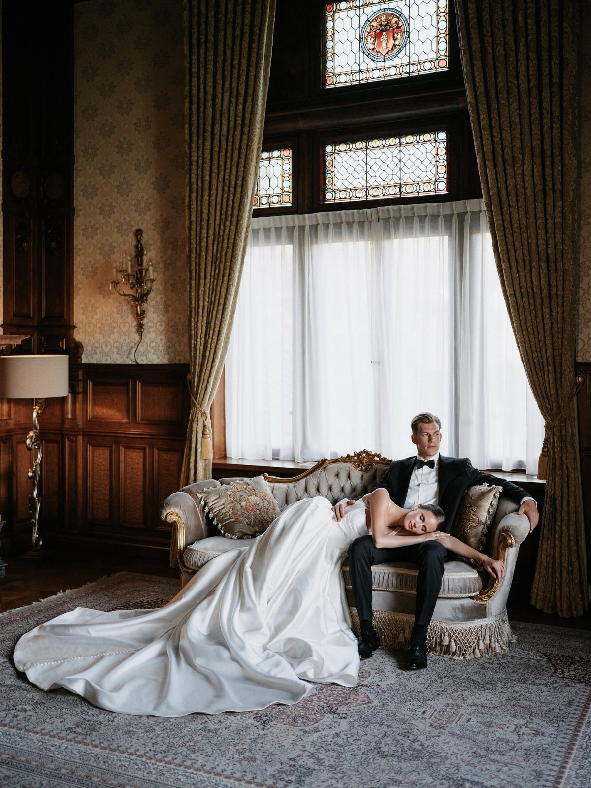 Bride and groom posing in a high-fashion, editorial style within a luxurious vintage room.