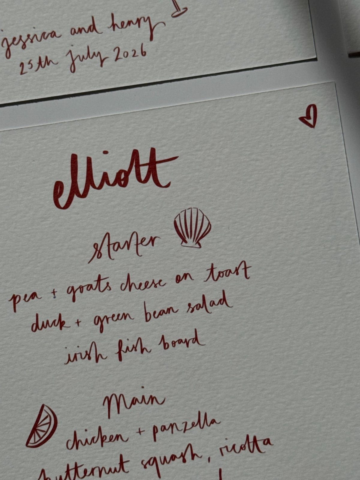 Handwritten red ink menu on white textured paper with food options and doodles.