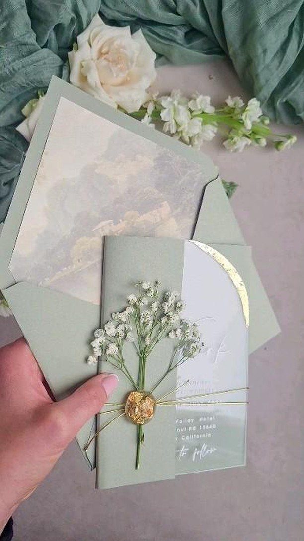 Sage green wedding invitation suite with gold wax seal and baby's breath flowers.