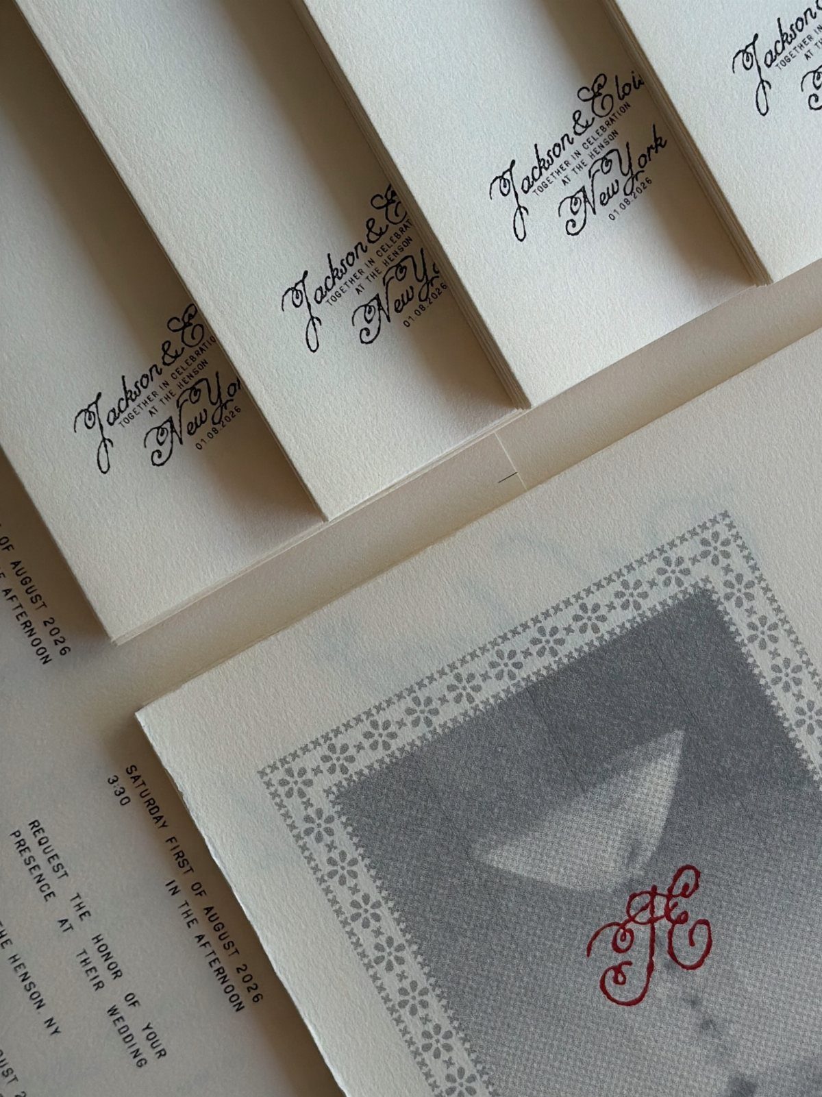Wedding invitation cards with a translucent vellum overlay and red monogram detail.