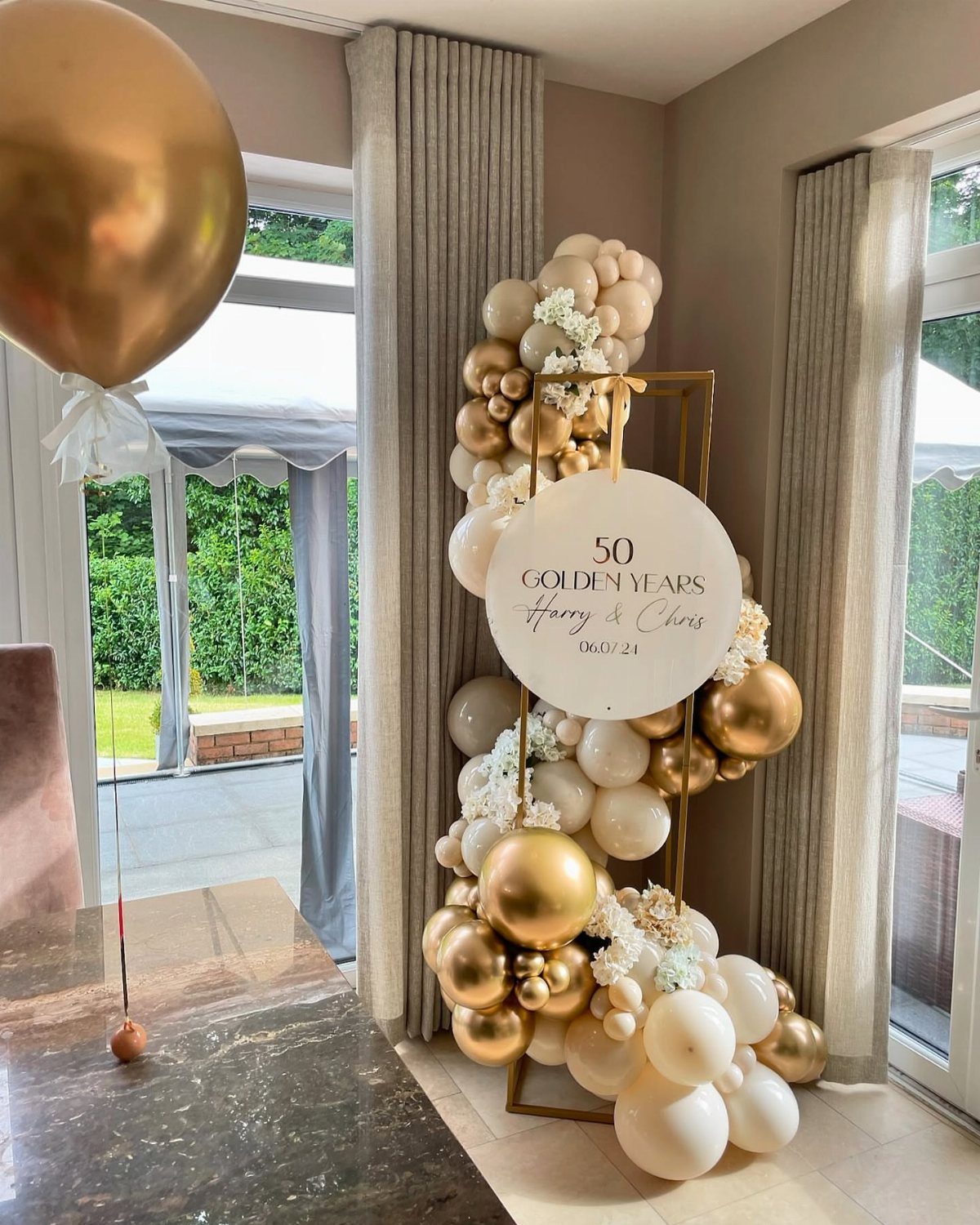 Gold and white balloon installation with a 50th anniversary sign in a room.