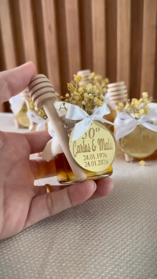 Small honey jars with gold tags and ribbons as anniversary party favors.