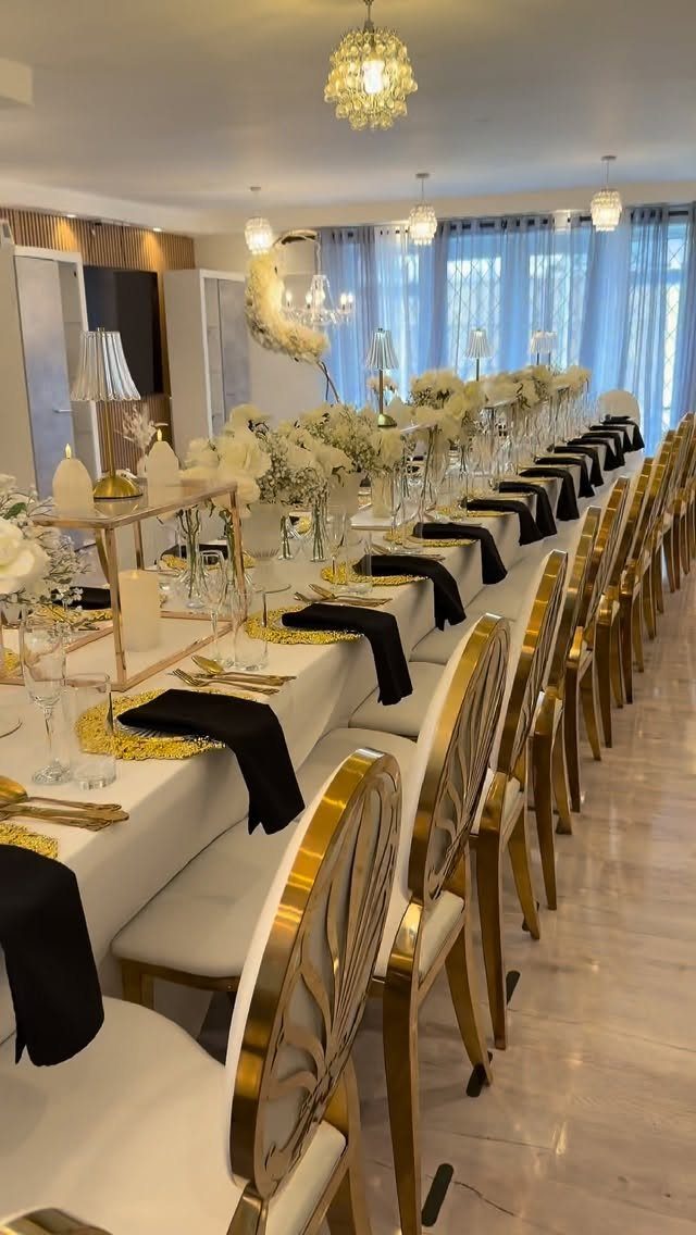 Formal banquet table with gold and white decor and black napkins for anniversary.