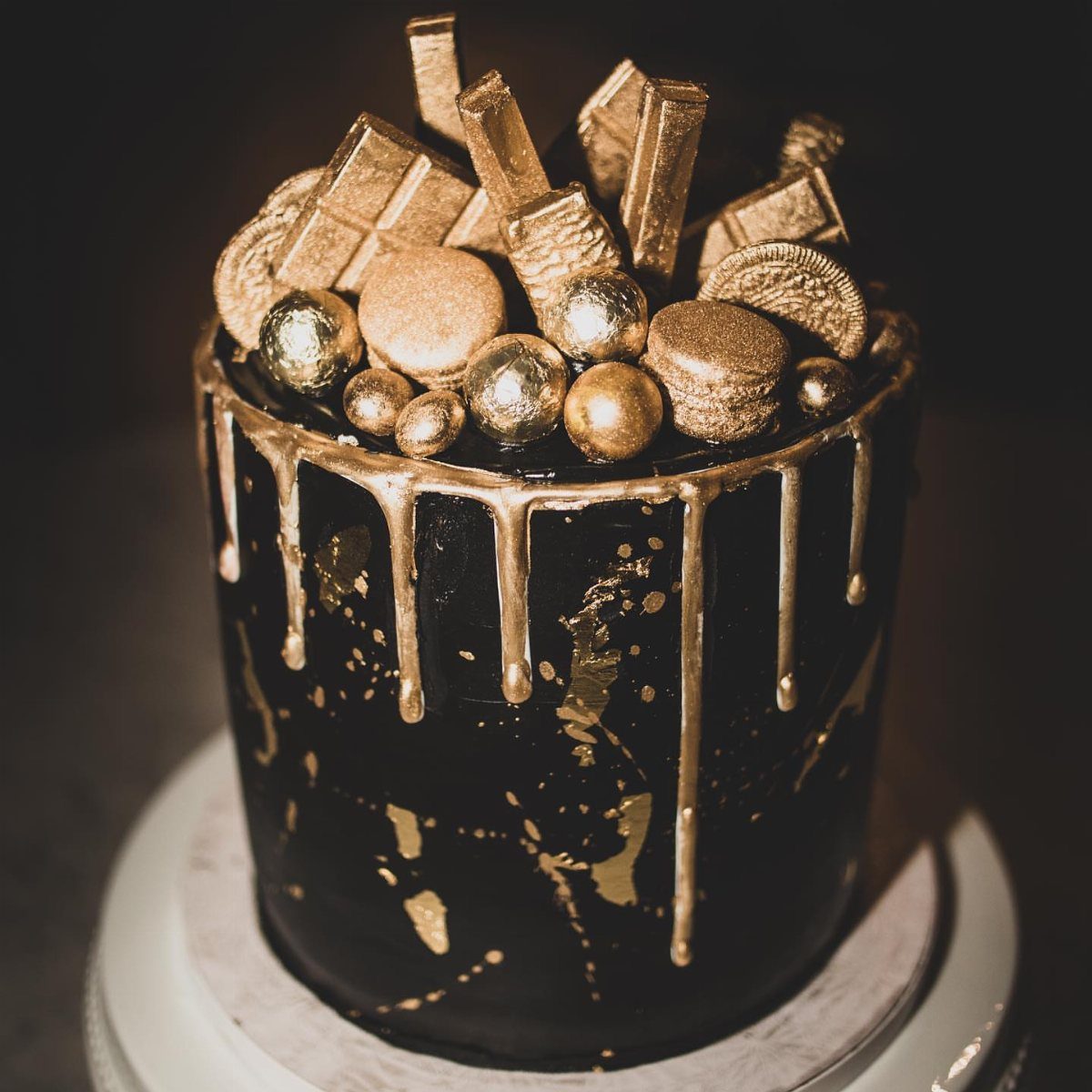 Dark chocolate cake with gold drip icing and gold-painted dessert toppings.