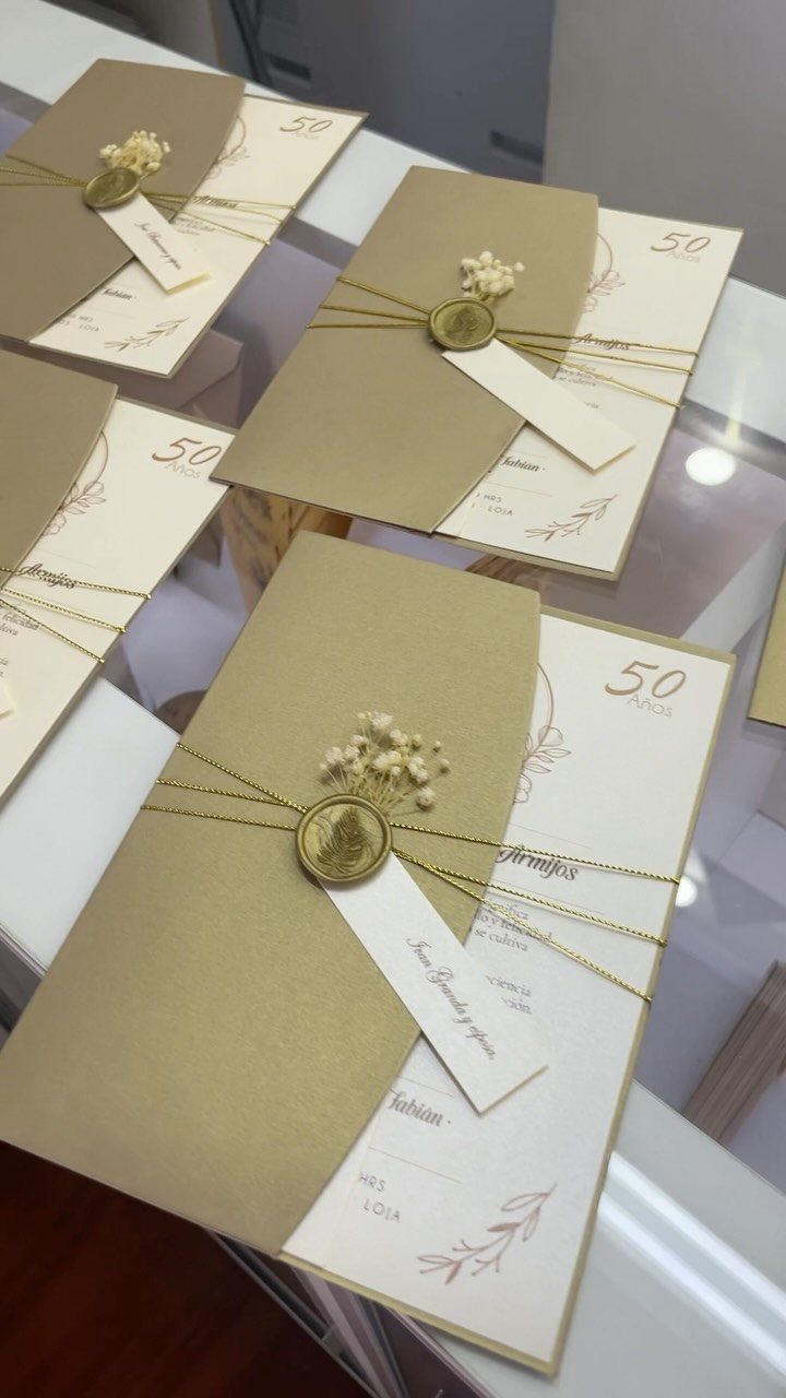 Gold invitation cards tied with string and wax seals for a 50th anniversary.