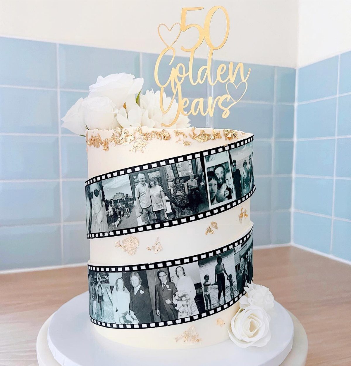 White anniversary cake with edible photo film strips and gold 50th anniversary topper