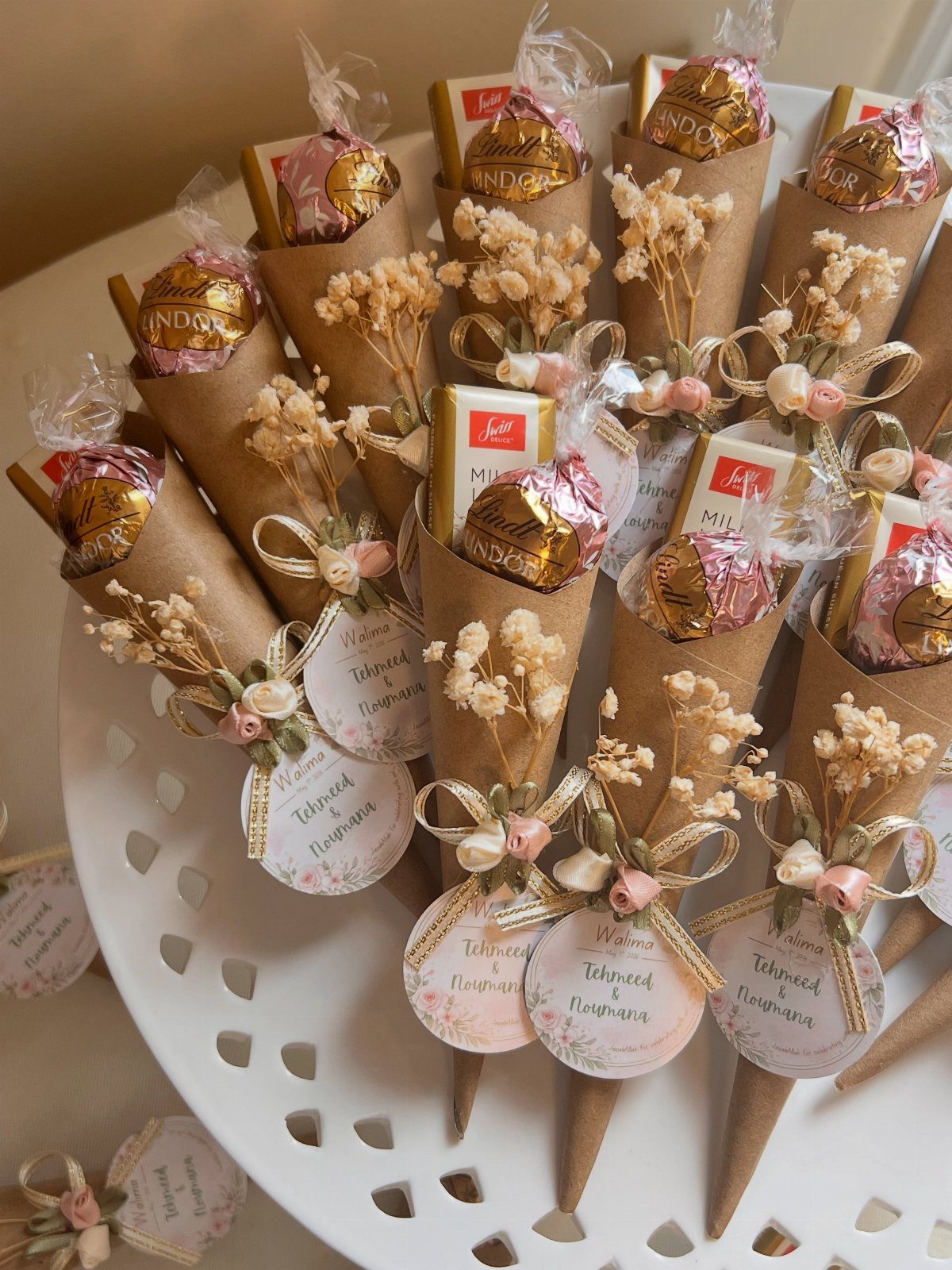 Small brown paper cones with chocolates and dried flowers as wedding favors.