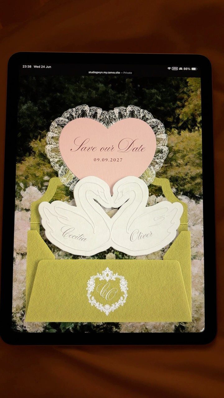 Save-the-date wedding invitation design with pink heart and white swans on a tablet.