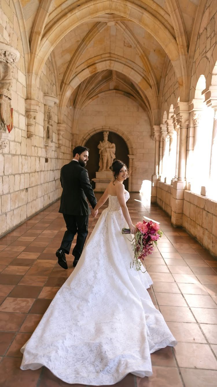 Bride and groom walking through a stone vaulted corridor during their wedding photoshoot.