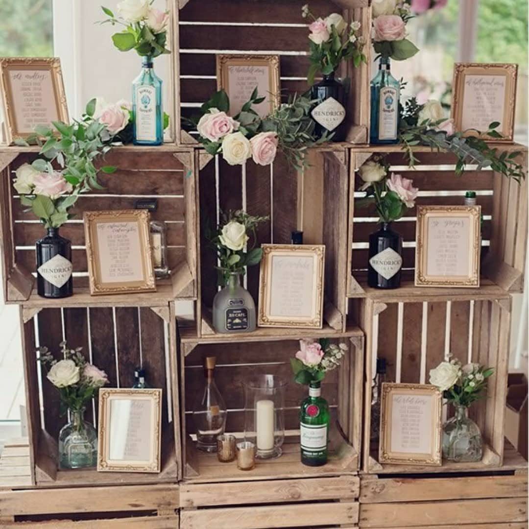 Stacked wooden crates decorated with pink roses and gold frames for a wedding.