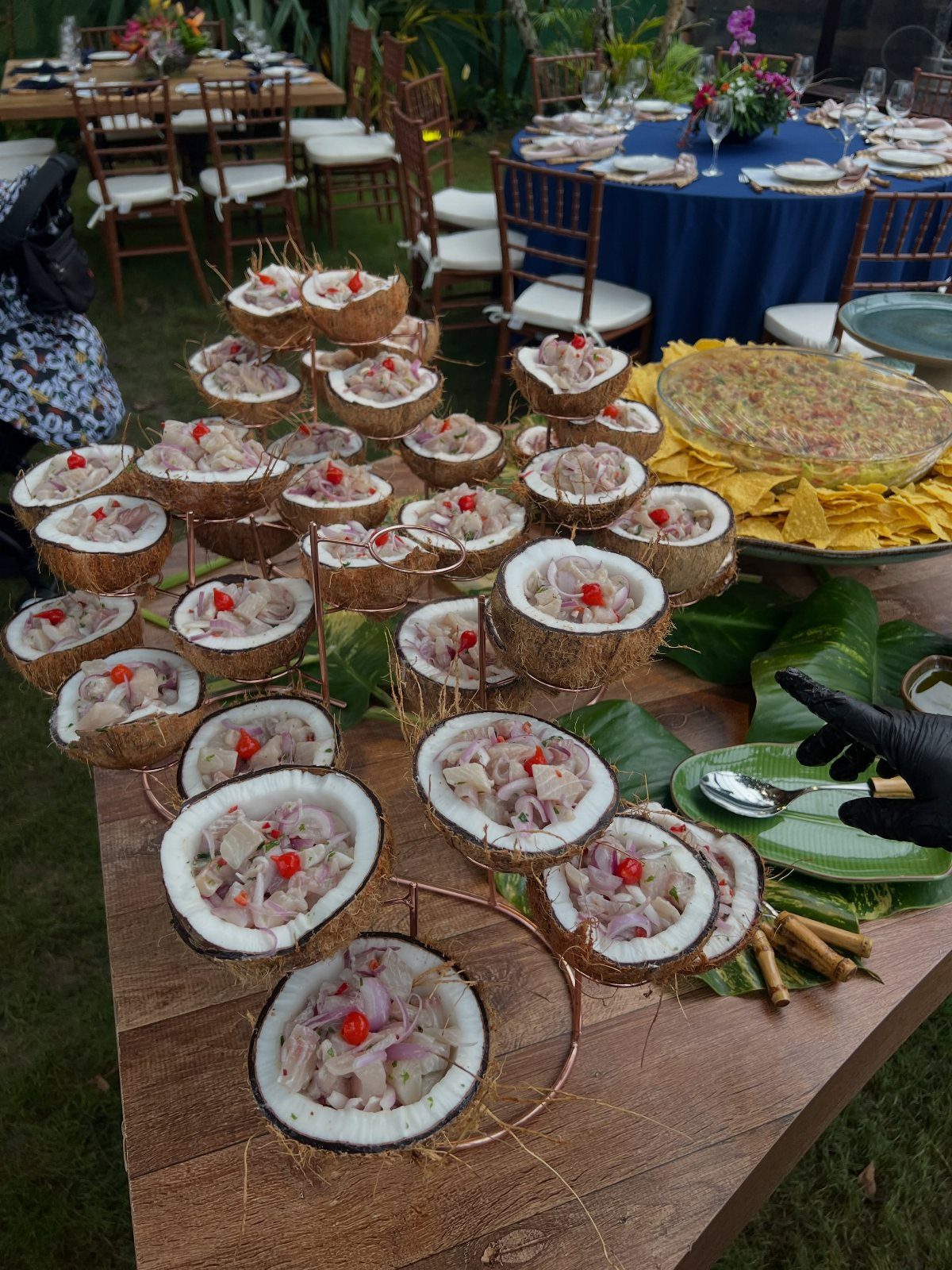 Appetizers served in coconut shells on a wooden table at a beach event