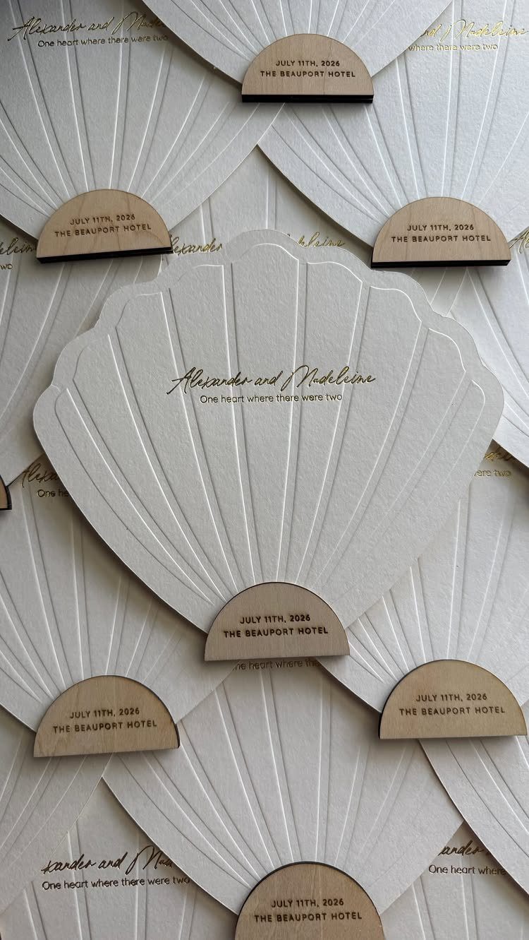 White shell-shaped hand fans with elegant cursive text and brown handles.