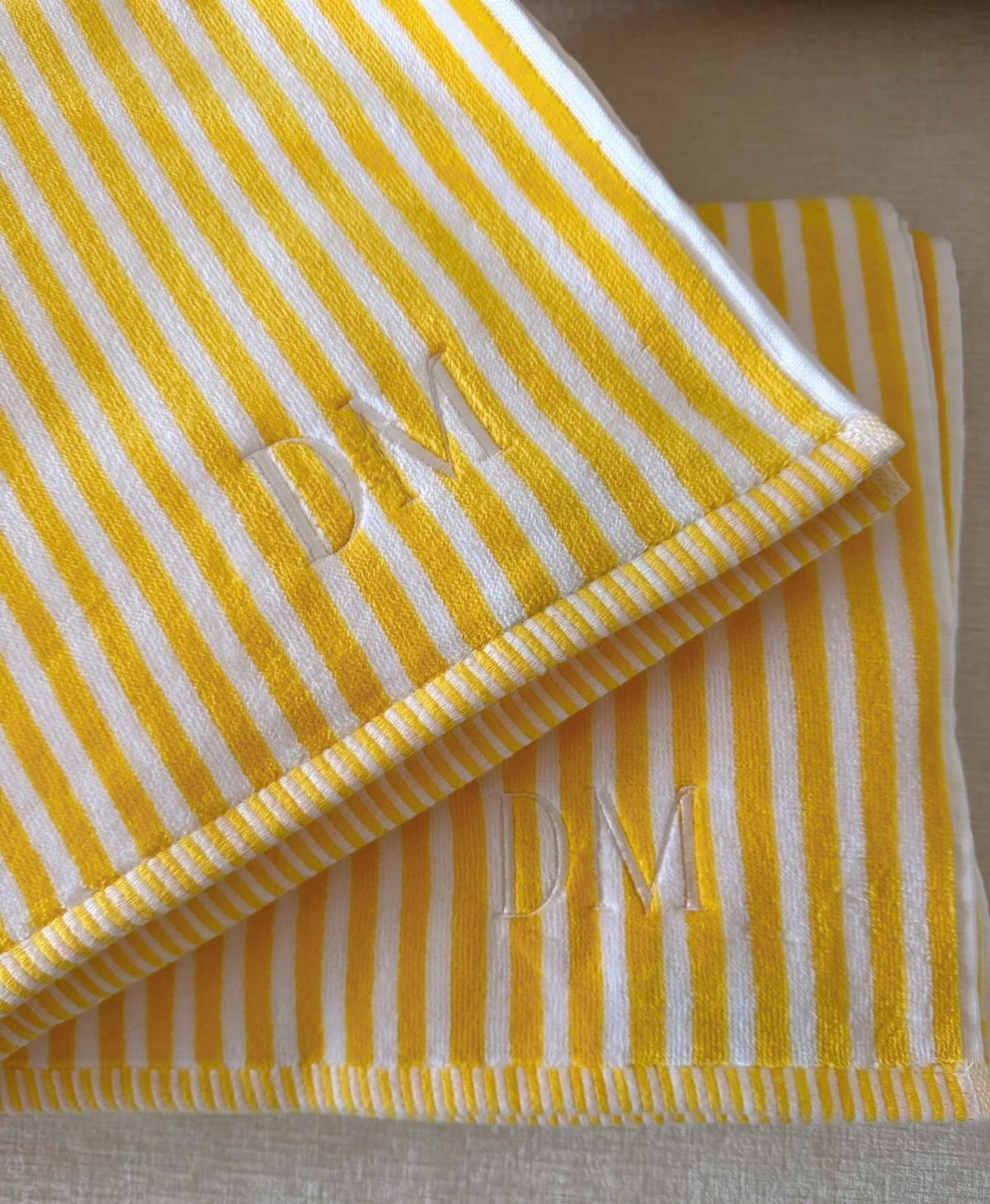 Yellow and white striped beach towels with white embroidered initials DM.