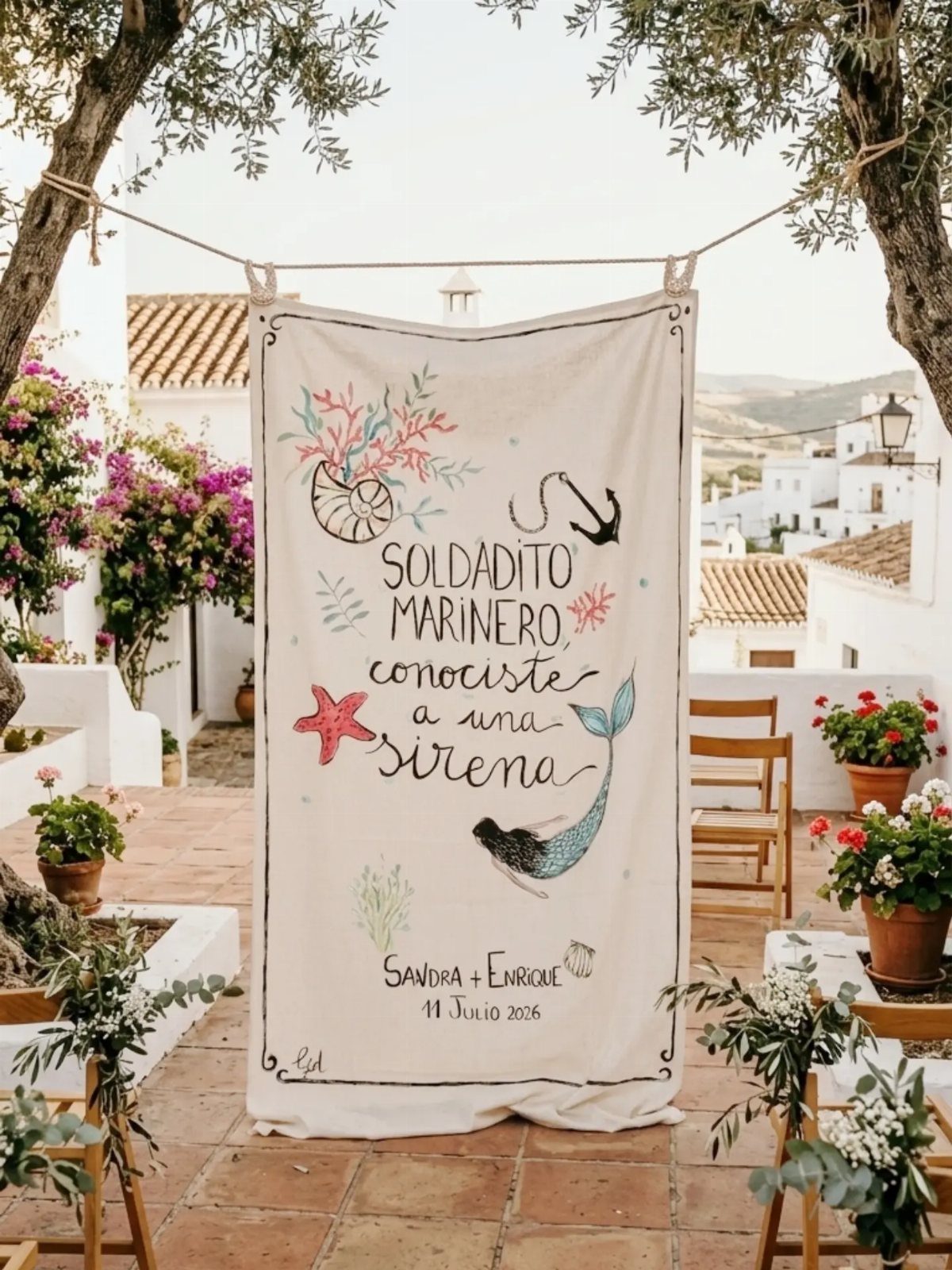 Nautical fabric banner hanging from a rope between trees in a sunny courtyard.