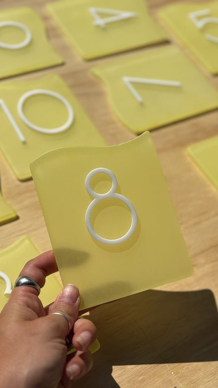 Yellow glass table number tiles on a wooden surface held by a hand