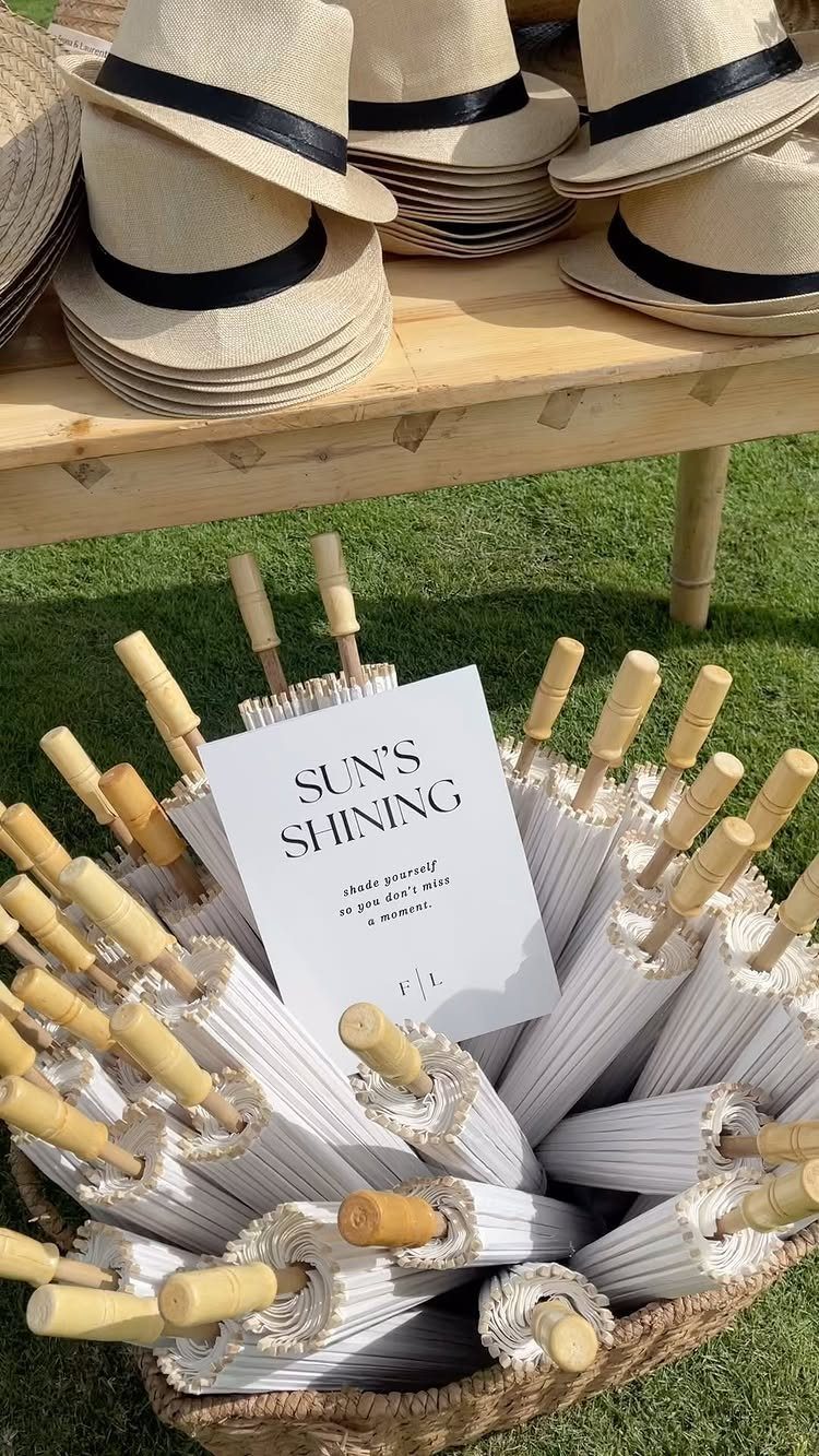 White parasols in a wicker basket and straw hats on a wooden table.