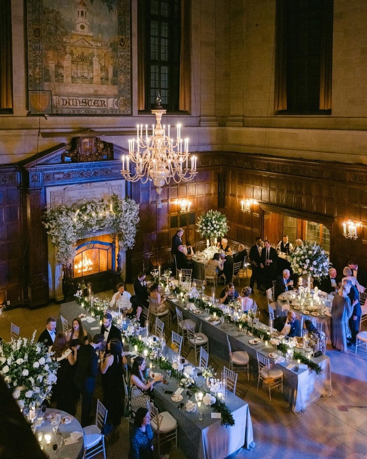 Formal wedding reception with guests at long tables in a wood-paneled grand hall.