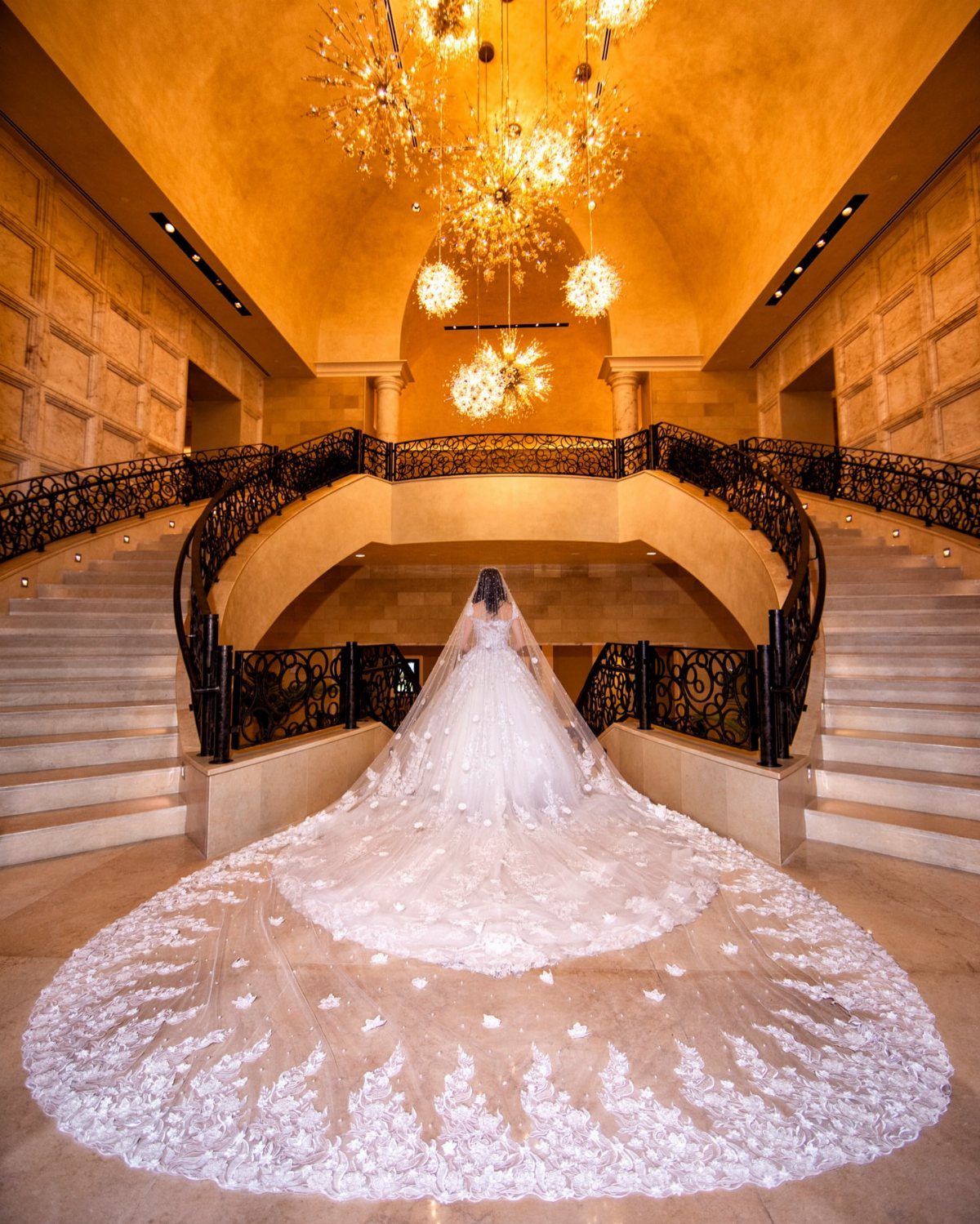 Bride in a white lace gown with a long train in a grand hall