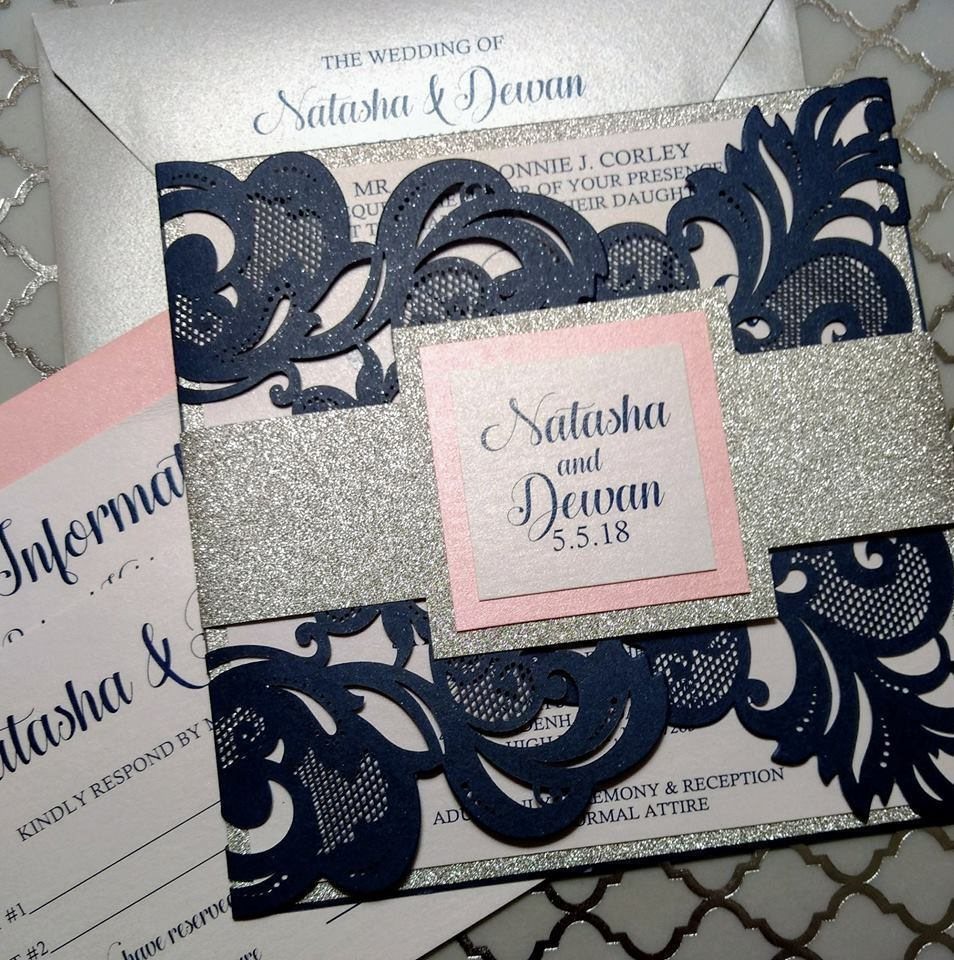 Navy blue laser-cut floral wedding invitation with silver glitter band and blush pink card.