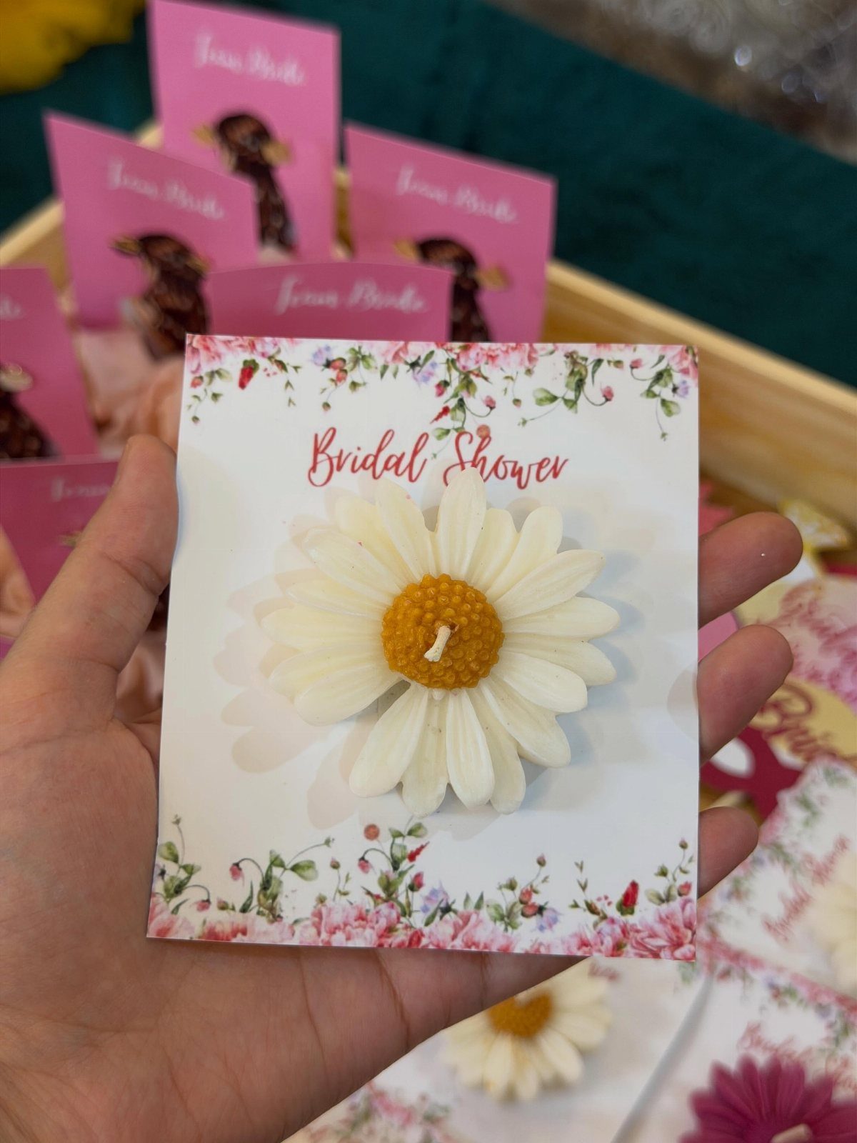 Daisy-shaped mini candle on a floral bridal shower card held by a hand