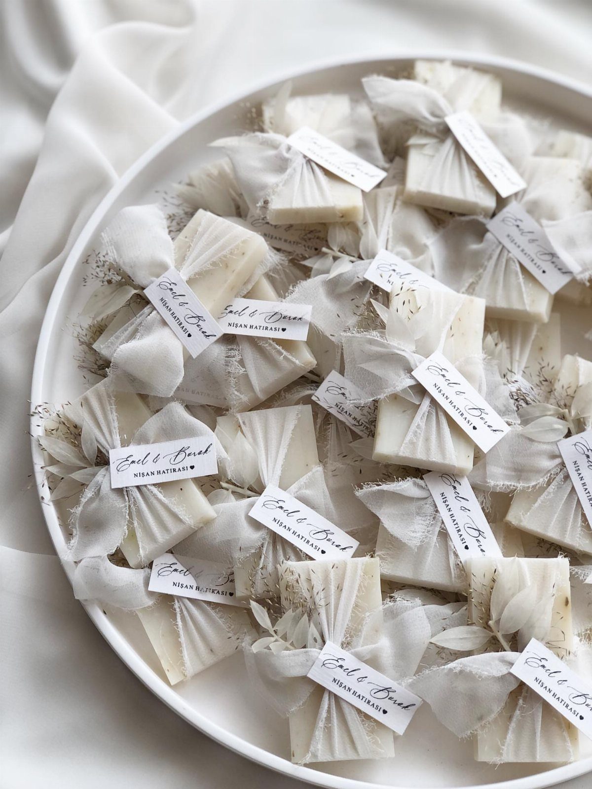 White soap bars wrapped in sheer fabric with tags on a white plate
