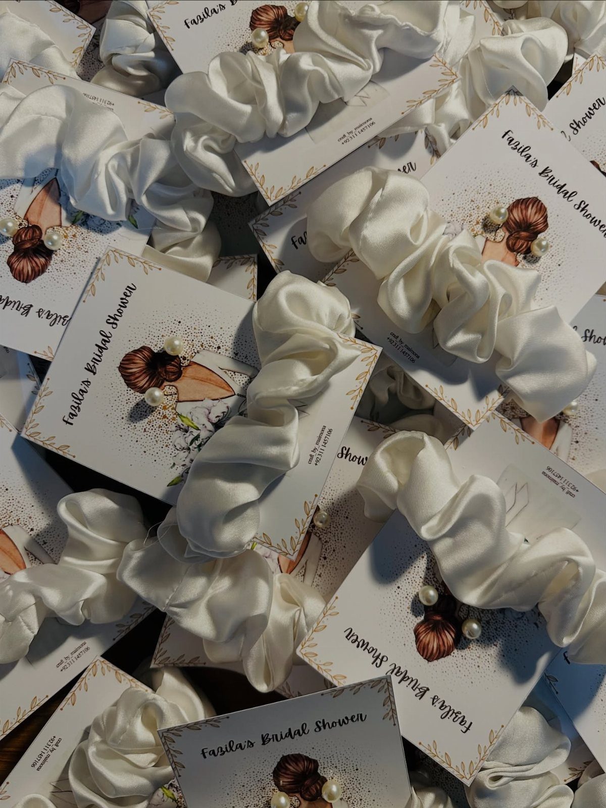 White satin scrunchies on bridal shower tags with decorative beads and illustrations.