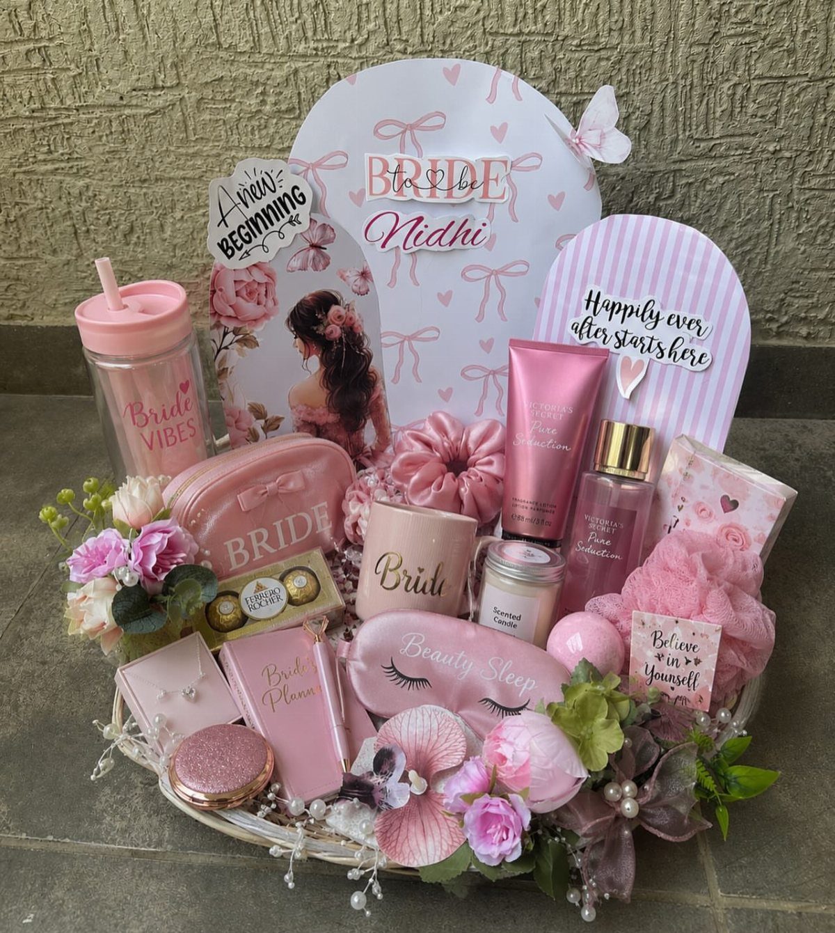 Bridal gift basket filled with pink beauty products, accessories, and floral decorations.