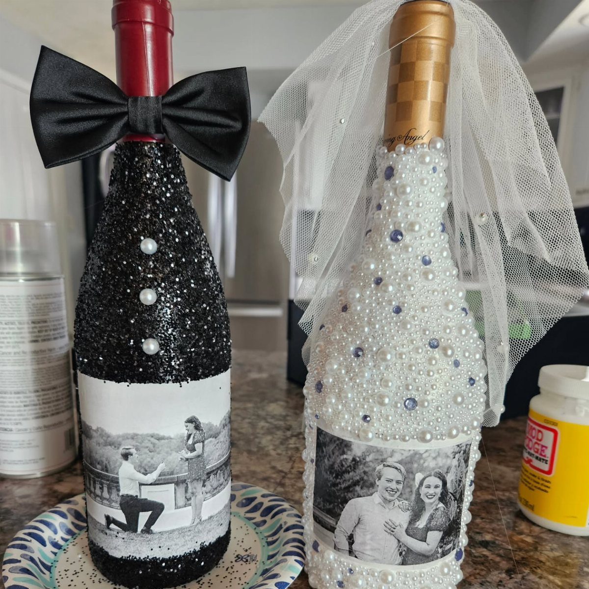 Two wine bottles decorated as a bride and groom with photos and accessories.