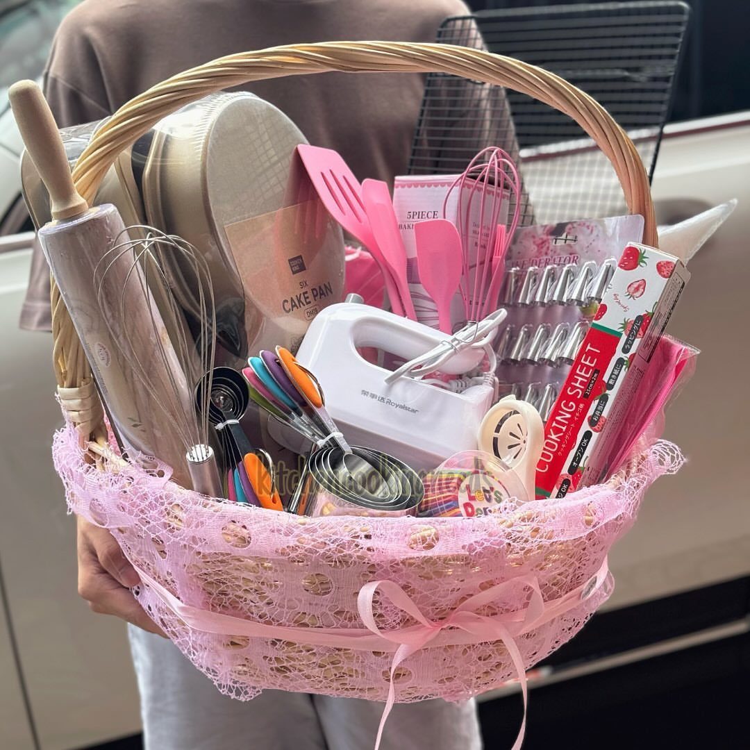 Baking gift basket with pink lace, containing a mixer, whisks, and spatulas.