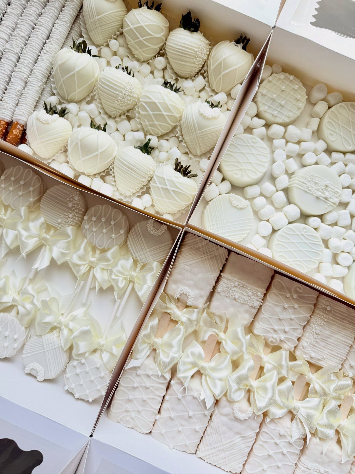 White chocolate covered strawberries, cake pops, and marshmallows arranged in a white box.