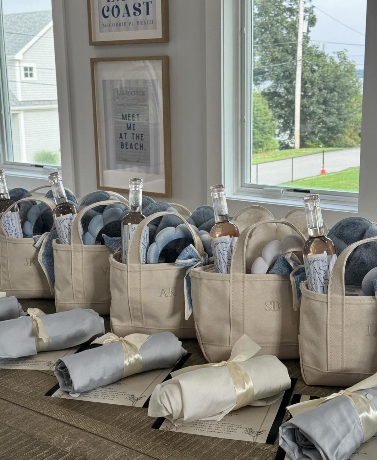 Beige canvas tote bags with wine and blue blankets next to rolled pashminas.
