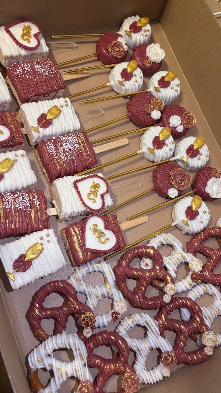 Decorated chocolate cake pops, bars, and pretzels in a cardboard box.
