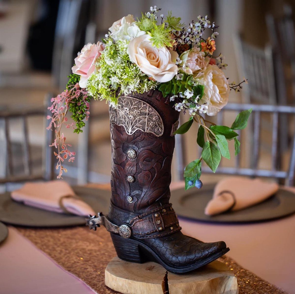 Cowboy boot floral arrangement resting on a wooden tree slice table centerpiece