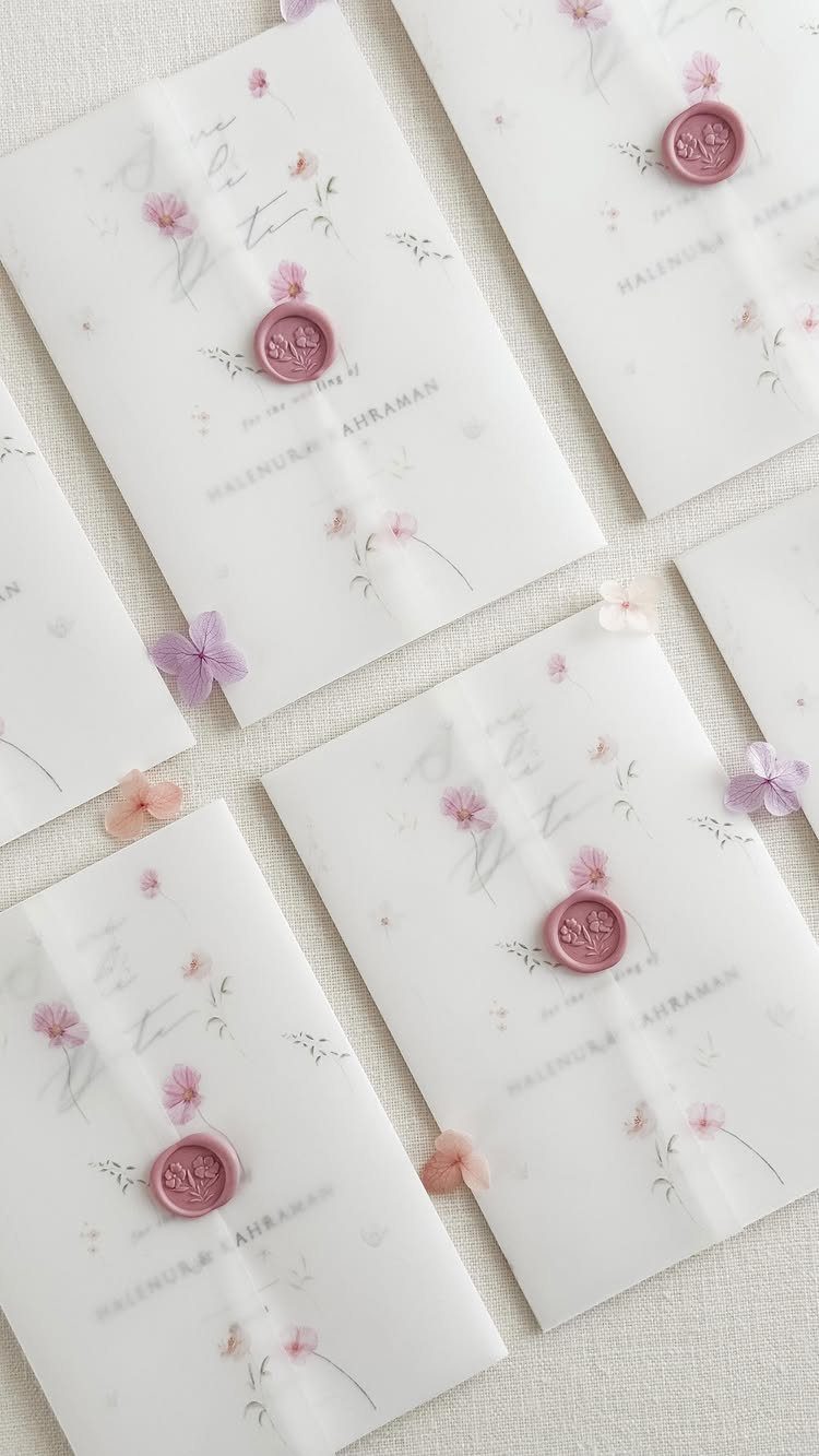 Vellum save the date cards with pink floral designs and wax seals.