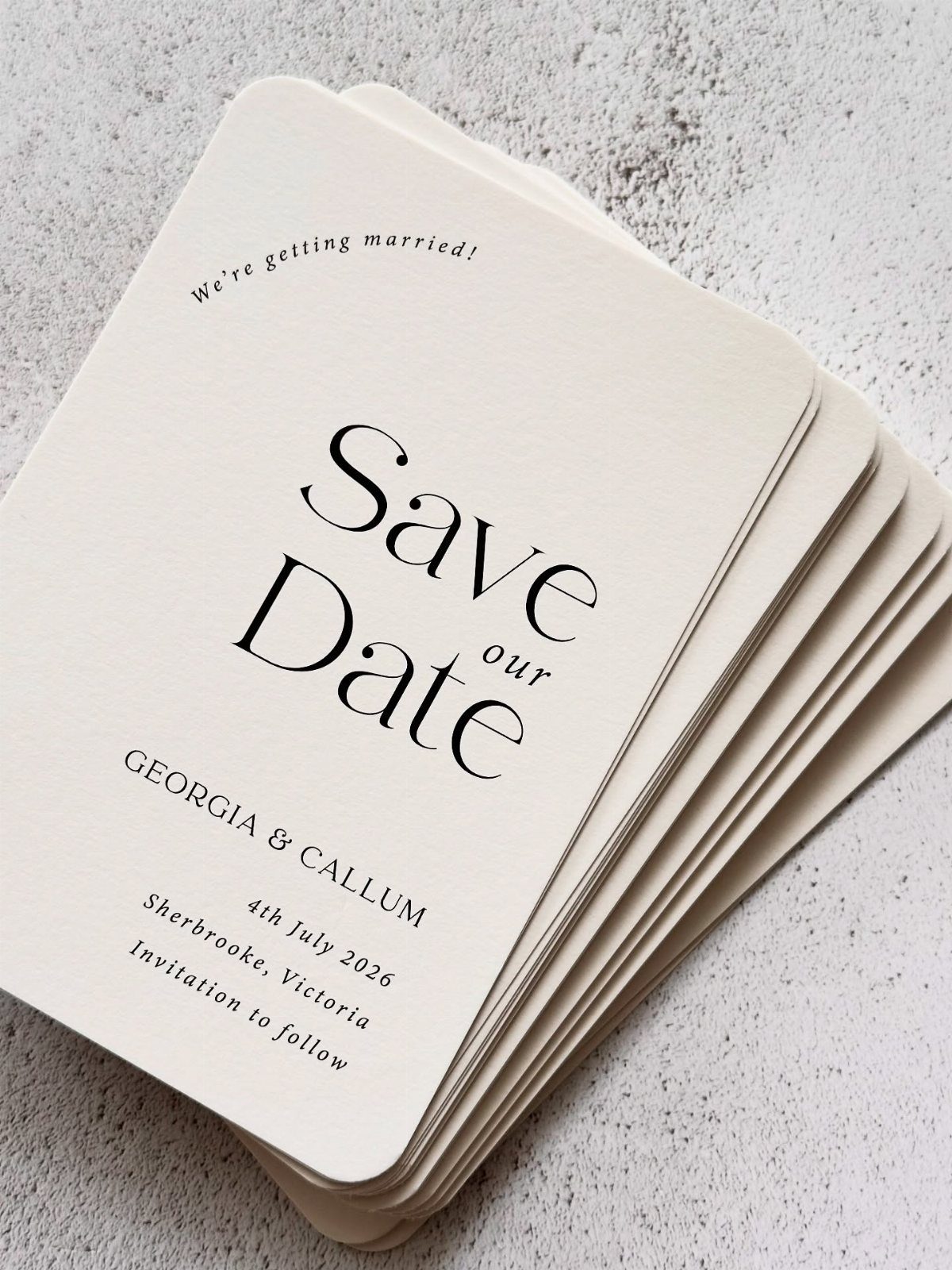 Stack of cream minimalistic save the date cards with elegant black serif typography.