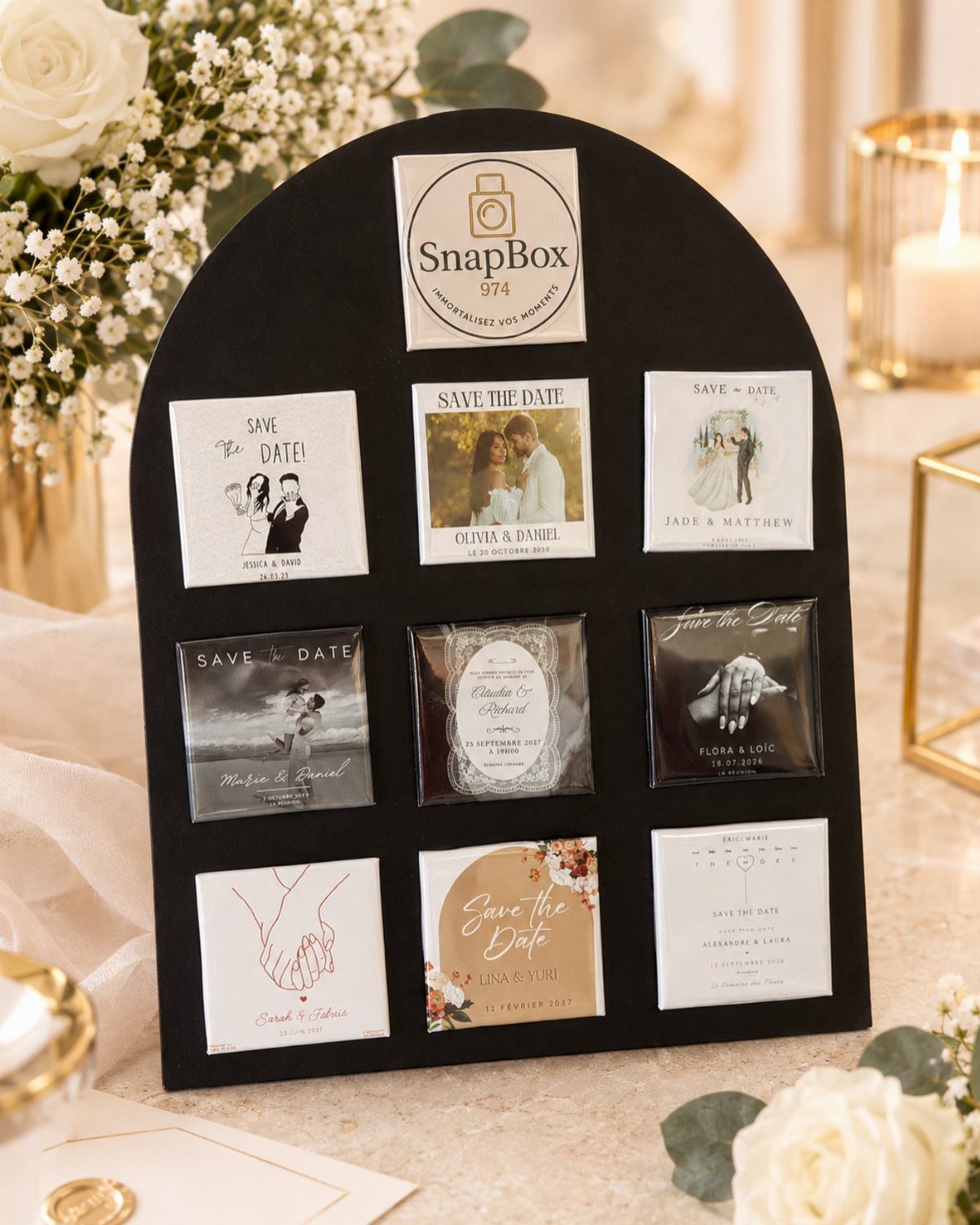 Black arched display board showcasing various square save-the-date card designs with floral accents.