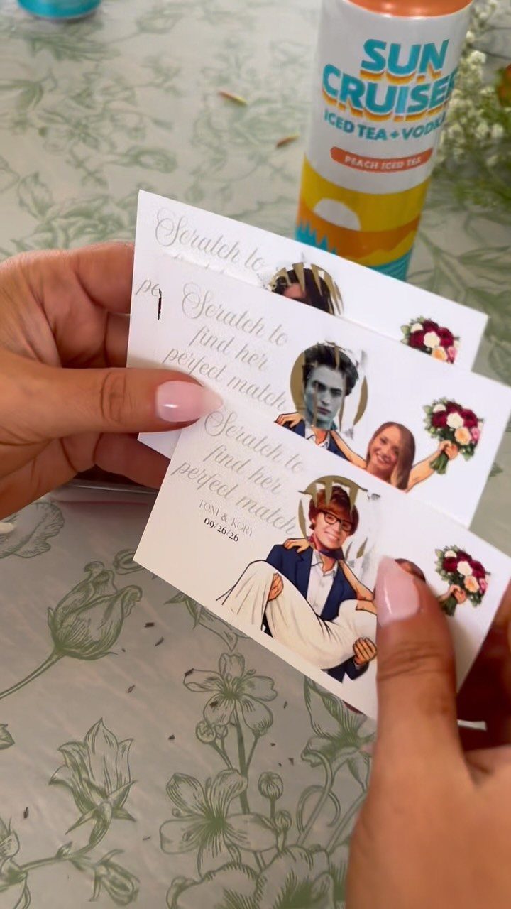 Hands holding white scratch-off save the date cards with illustrated couple portraits.