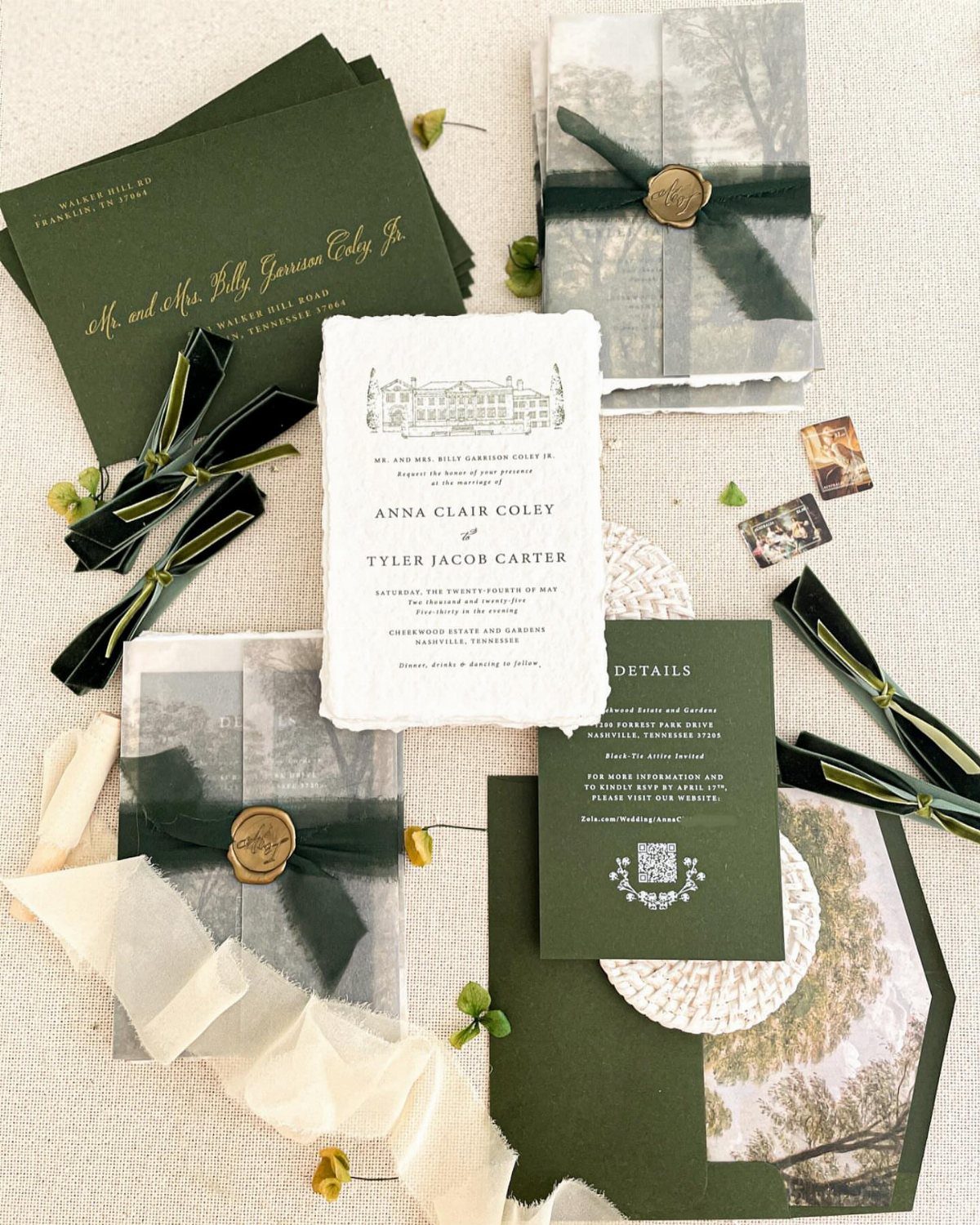 Wedding invitation suite with forest green envelopes, white deckle-edged paper, and gold wax seals.