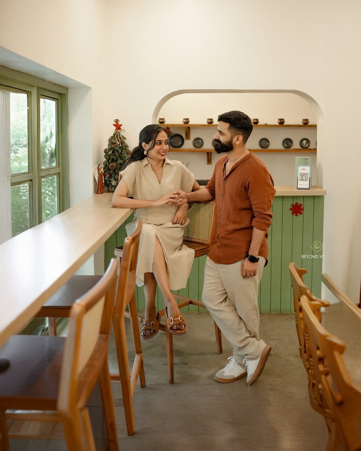 Couple holding hands and smiling at each other in a bright indoor setting.