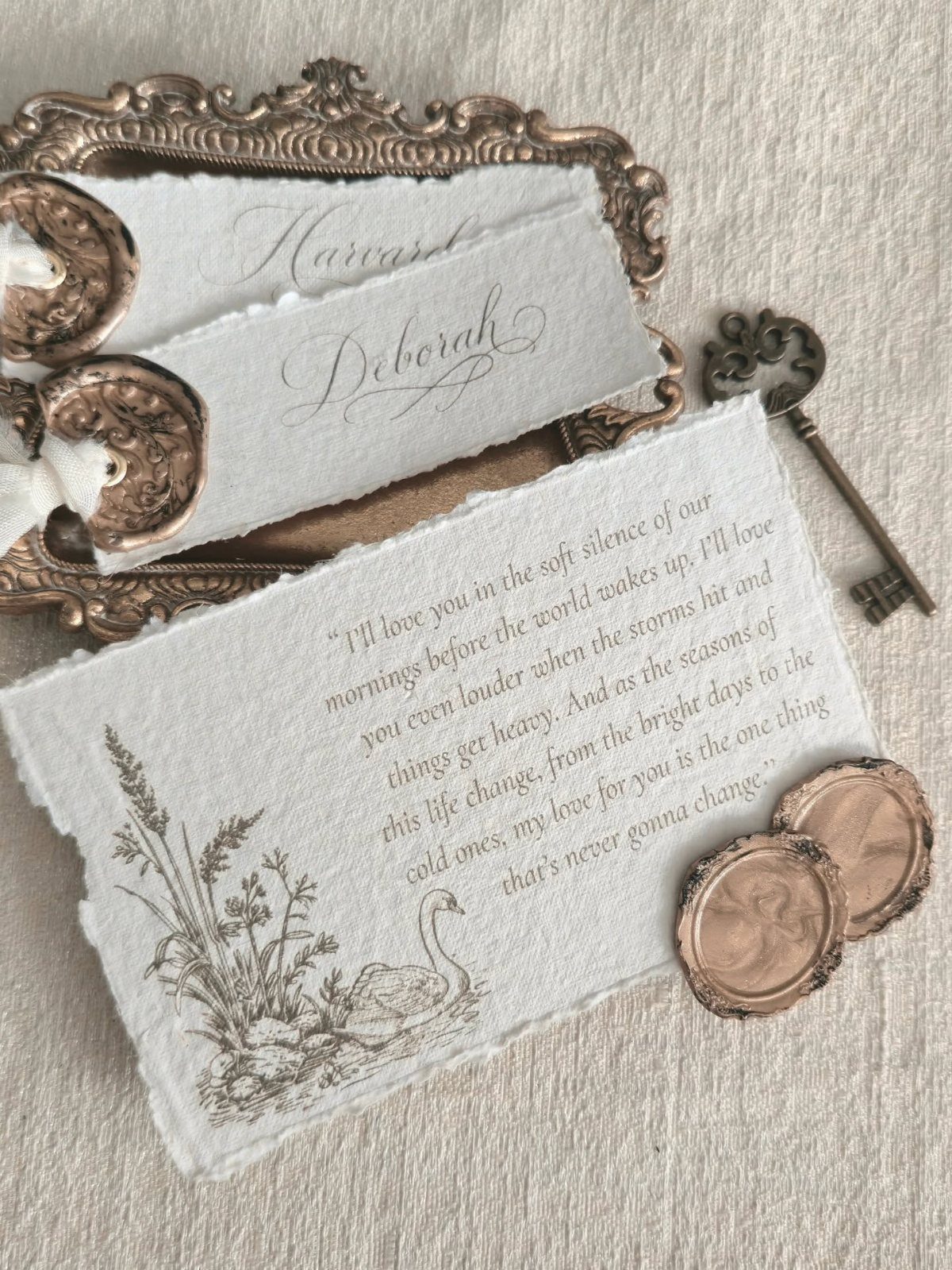 Deckle-edged wedding cards with bronze wax seals and an ornate vintage key.