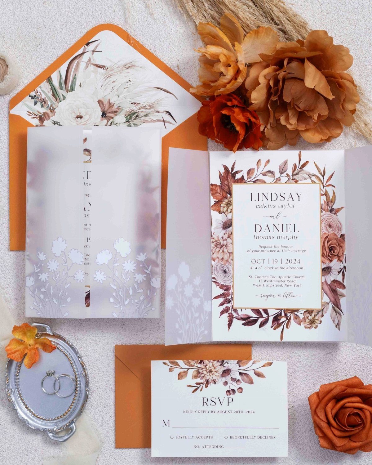 Wedding invitation suite with orange floral accents, vellum wrap, and matching orange envelope.