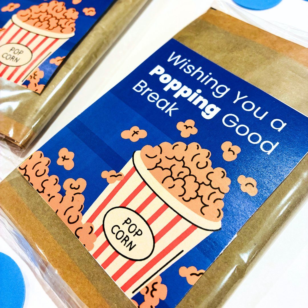 Popcorn snack bags with blue labels and a popcorn illustration for wedding favors.