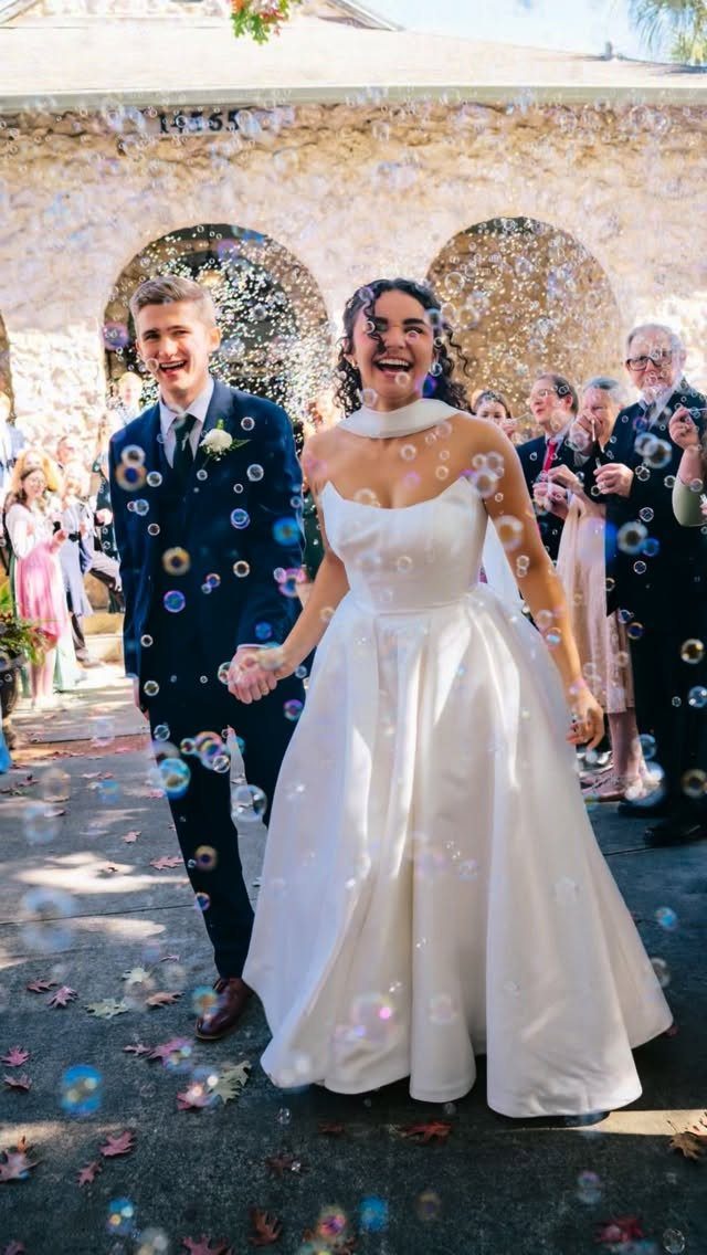 Newlywed couple walking through bubbles and confetti during their wedding grand exit.