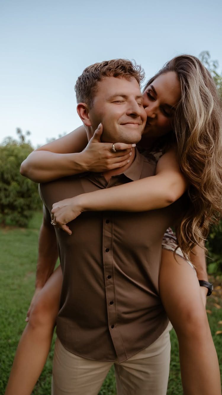 Couple embracing outdoors with woman giving man a kiss on the cheek