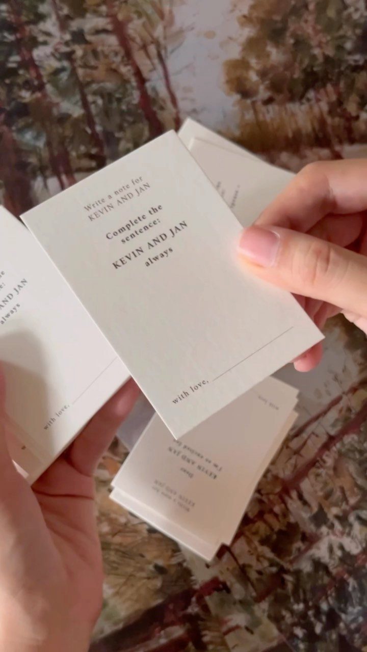 Hands holding white prompt cards for guests to write messages for a couple.