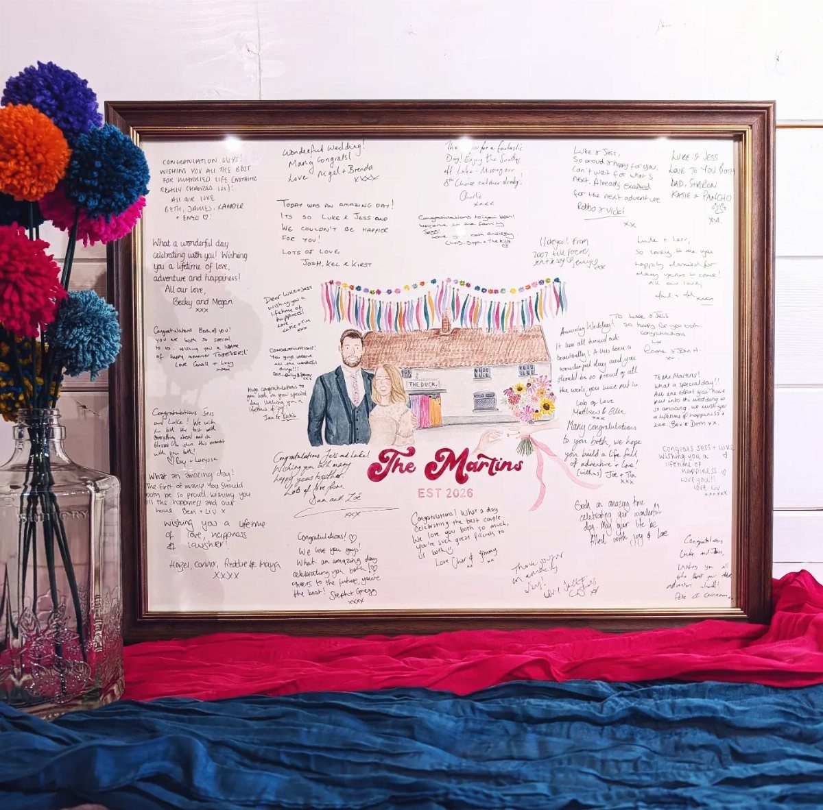Framed custom wedding artwork with a couple's illustration and guest signatures around it.