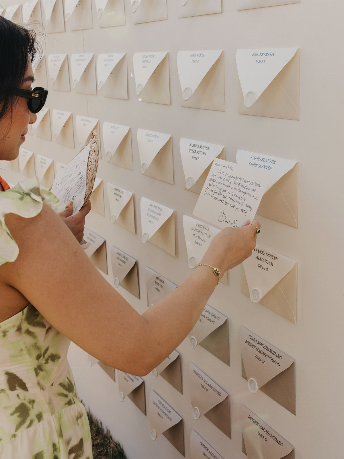Woman reading a handwritten note from a wall of white guest book envelopes